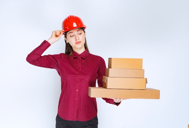 Portrait of a young woman in crash helmet holding paper boxes . 