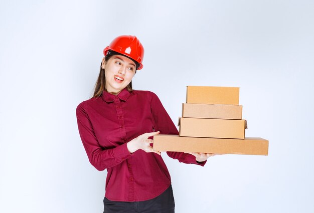 Portrait of a young woman in crash helmet holding paper boxes . 