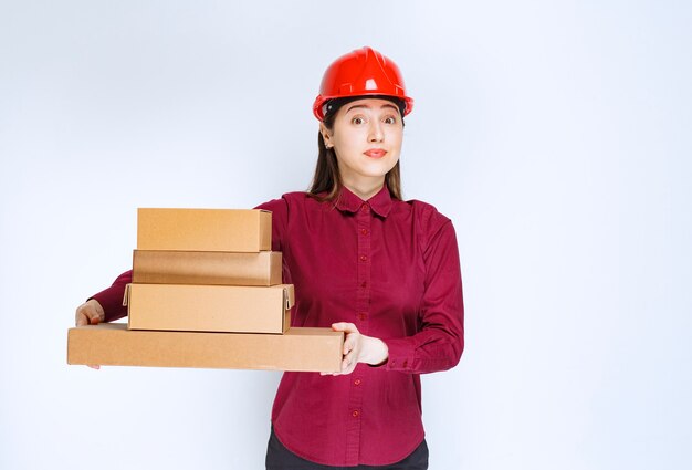 Portrait of a young woman in crash helmet holding paper boxes . 