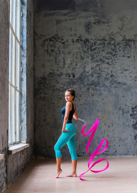 Portrait of a young woman dancing with pink ribbon