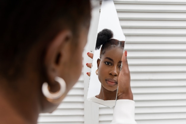 Free photo portrait of young woman dressed in white posing in the mirror