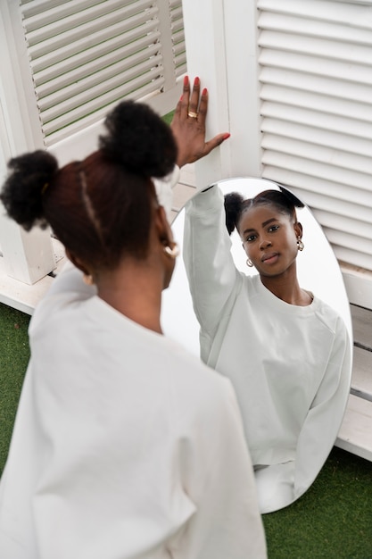 Free photo portrait of young woman dressed in white posing in the mirror