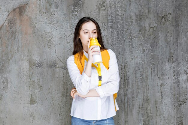 Portrait of young woman drinking bottle of water. High quality photo