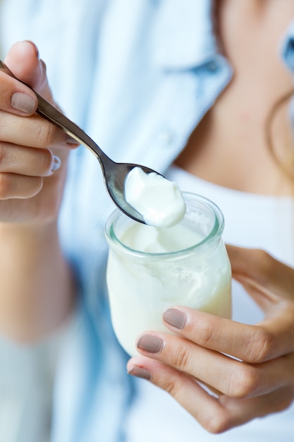 Portrait of young woman eating yogurt.