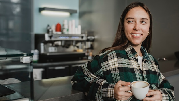 Free photo portrait of a young woman enjoying coffee
