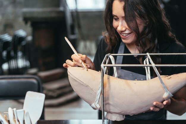 Portrait of young woman enjoying favorite job in workshop. potter carefully works on the clay whale