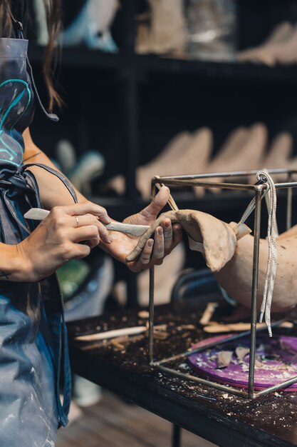 Portrait of young woman enjoying favorite job in workshop. potter carefully works on the clay whale