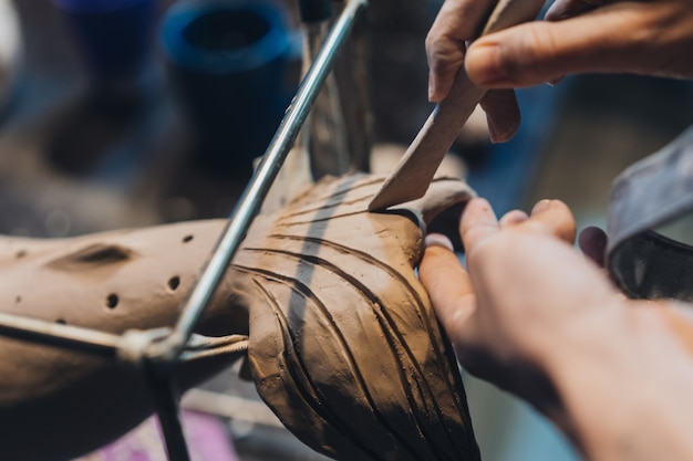 Portrait of young woman enjoying favorite job in workshop. potter carefully works on the clay whale