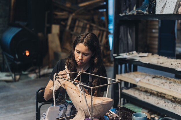 Портрет молодой женщины, наслаждающейся любимой работой в мастерской. Гончар тщательно работает над глиняным китом.