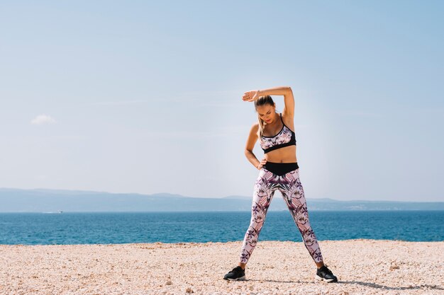 Portrait of a young woman exercising near the beach