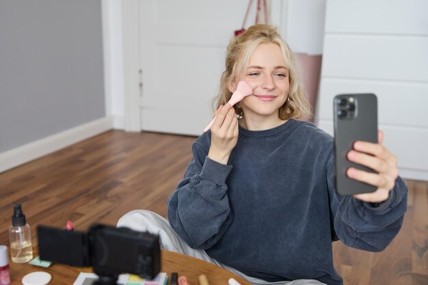 Portrait of young woman girl beauty blogger recording vlog in her bedroom doing makeup tutorial for