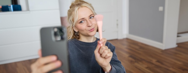 Portrait of young woman girl beauty blogger recording vlog in her bedroom doing makeup tutorial for