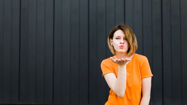 Portrait of a young woman giving flying kiss