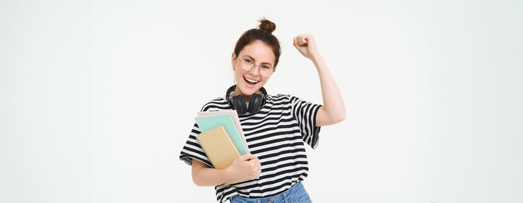Free Photo portrait of young woman in glasses wearing headphones over neck holding planner notebooks and study