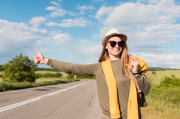 Free photo portrait of young woman hitchhiking