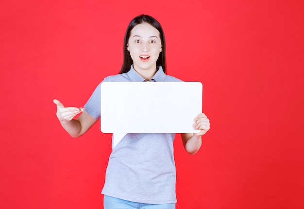 Portrait of young woman holding board and point hand on it