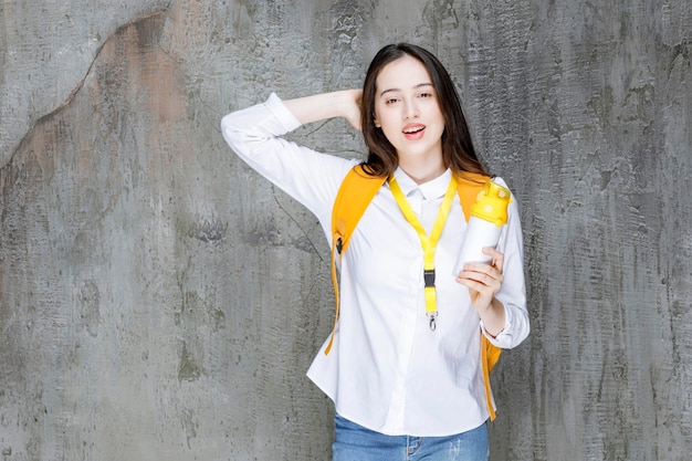 Portrait of young woman holding bottle of water and standing. High quality photo