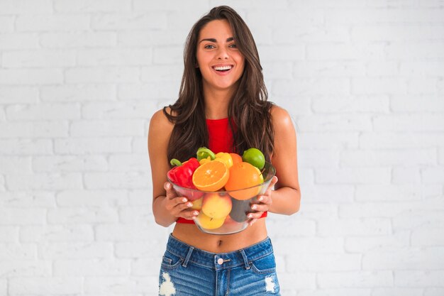 新鮮な野菜や果物のボウルを保持している若い女性の肖像