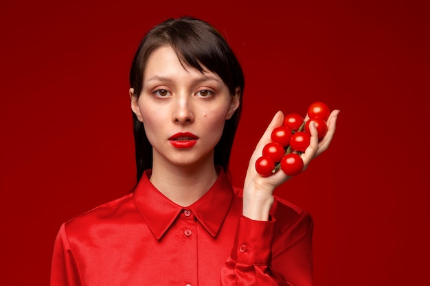 Foto gratuita ritratto di giovane donna che tiene i pomodorini