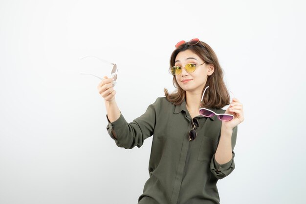 Portrait of young woman holding colorful sun glasses over white. High quality photo