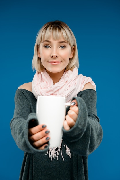 Portrait of young woman holding cup over blue wall