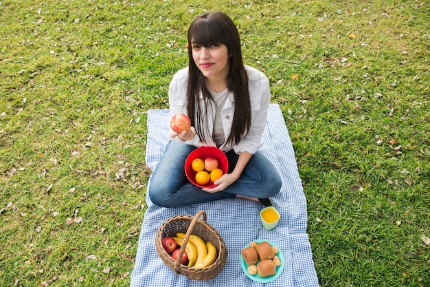 Portrait of young woman holding fresh fruits in the park