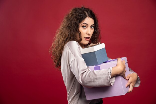 Ritratto di giovane donna che tiene strettamente i contenitori di regalo.