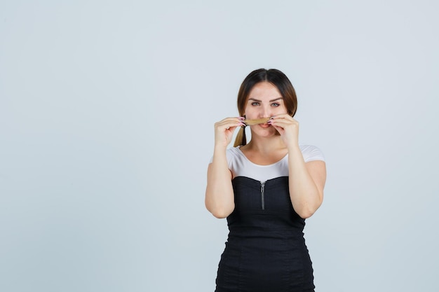 Portrait of young woman holding her hair as mustache