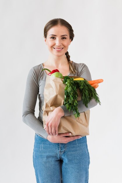 Portrait of young woman holding paper bag with groceries