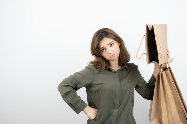 Portrait of young woman holding paper craft bags and standing. High quality photo