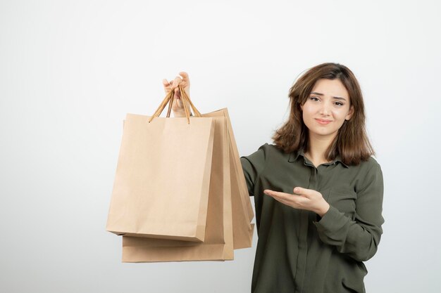 Портрет молодой женщины, держащей бумажные сумки и стоящей. Фото высокого качества