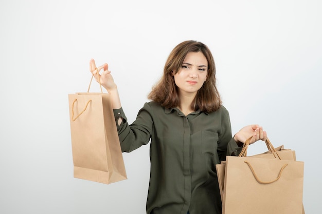 Portrait of young woman holding paper craft bags with angry expression. High quality photo