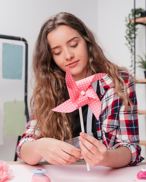 ピンクの折り紙の水玉模様の点線風車を保持している若い女性の肖像画