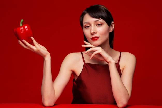 Portrait of young woman holding red bell pepper