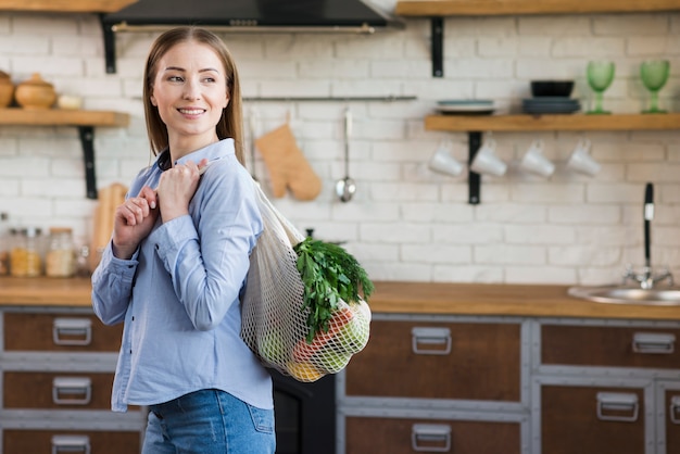 食料品と再利用可能なバッグを保持している若い女性の肖像画