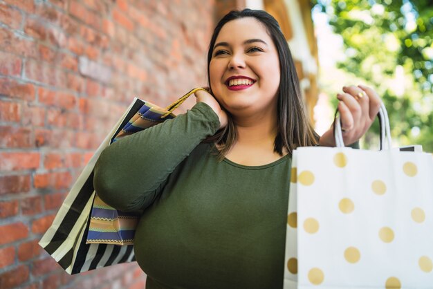 路上で屋外で買い物袋を保持している若い女性の肖像画