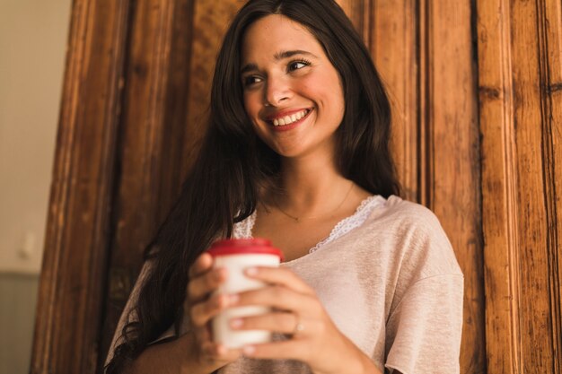 テイクアウトコーヒーカップを持っている若い女性の肖像画