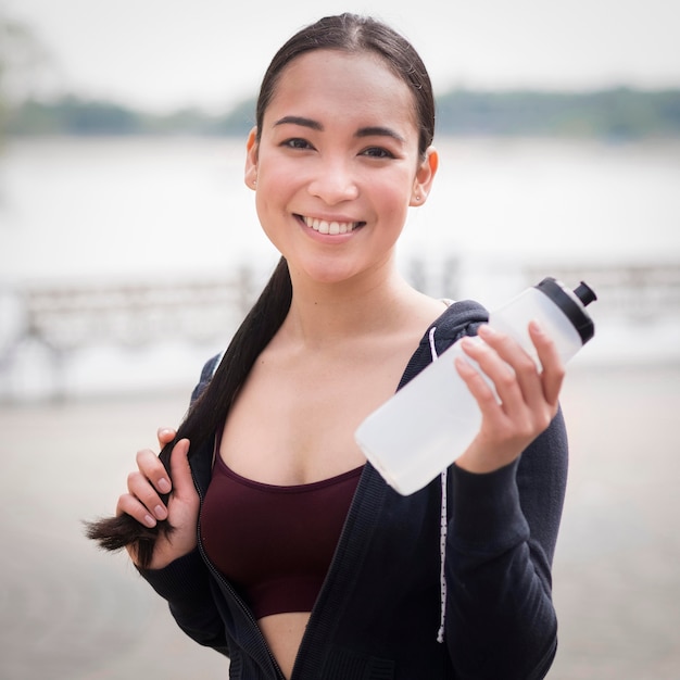 Foto gratuita ritratto della bottiglia di acqua della tenuta della giovane donna