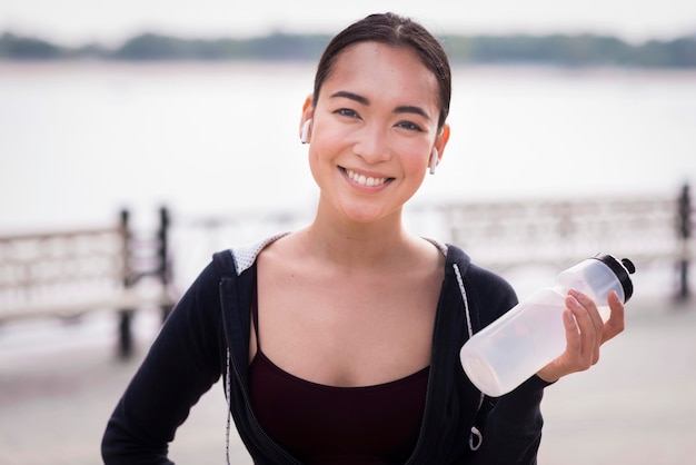 Foto gratuita ritratto della bottiglia di acqua della tenuta della giovane donna