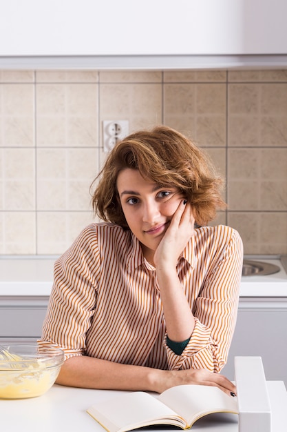 Портрет молодой женщины на кухне, глядя в камеру