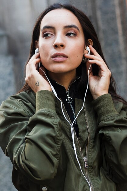 Portrait of a young woman listening music on white earphone