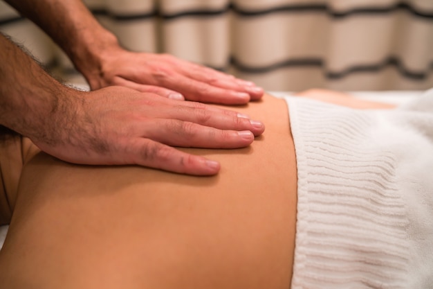 Portrait of young woman lying down on the table treatment and receiving relaxing back massage at the spa salon.