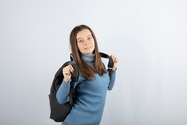 Портрет молодой женщины модели стоя с рюкзаком и позирует.