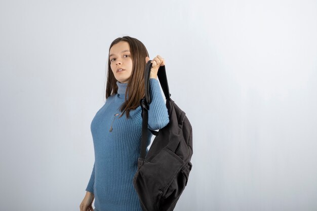 Portrait of a young woman model standing with backpack and posing.