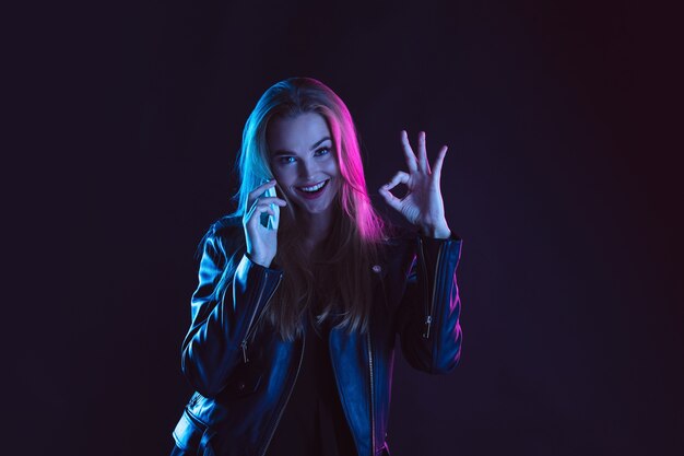 Portrait of young woman in neon light on dark backgound.