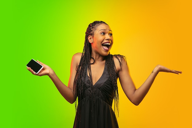 Portrait of young woman in neon light on gradient backgound.