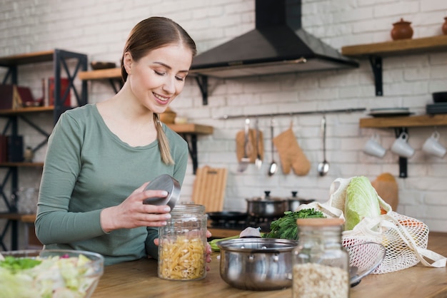 Portrait of young woman opening jar with organic pasta