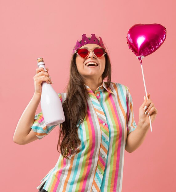 Portrait young woman at party with balloon and champagne bottle