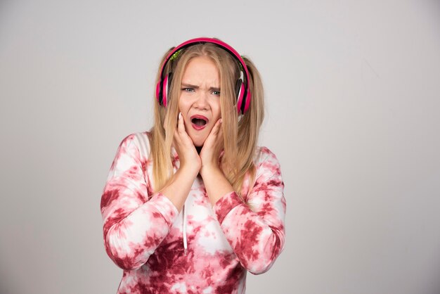 Portrait of young woman in pink outfit holding her face out of surprise.