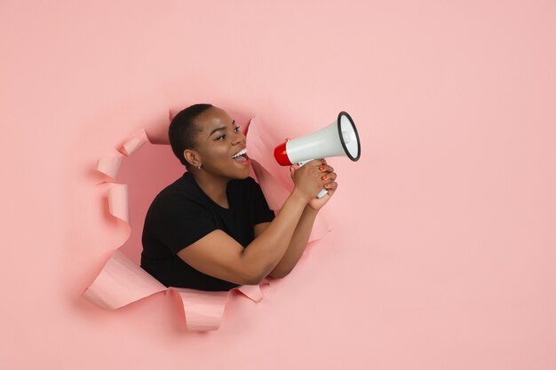 Portrait of young woman on pink torn breakthrought background